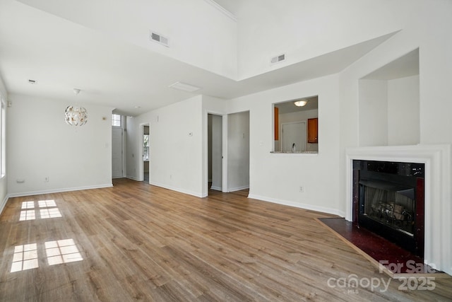 8605 Sawleaf Ct, Charlotte, NC 28215 - unfurnished living room with light wood-type flooring, baseboards, a fireplace with flush hearth, and a chandelier