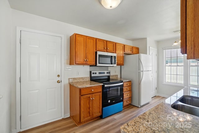 8605 Sawleaf Ct, Charlotte, NC 28215 - kitchen featuring stainless steel appliances, light wood-type flooring, brown cabinets, and baseboards