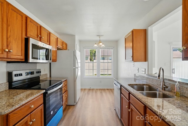8605 Sawleaf Ct, Charlotte, NC 28215 - kitchen featuring stainless steel appliances, a sink, light wood finished floors, light stone countertops, and brown cabinets