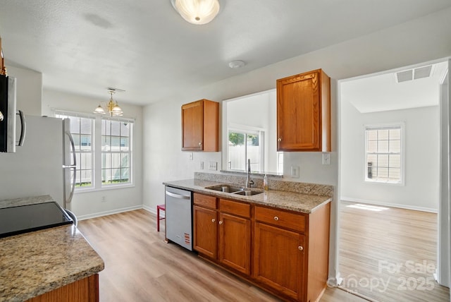 8605 Sawleaf Ct, Charlotte, NC 28215 - kitchen featuring stainless steel appliances, a sink, light wood-style flooring, and brown cabinets