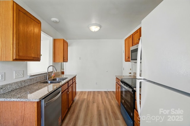 8605 Sawleaf Ct, Charlotte, NC 28215 - kitchen with stainless steel appliances, a sink, light wood finished floors, brown cabinets, and baseboards