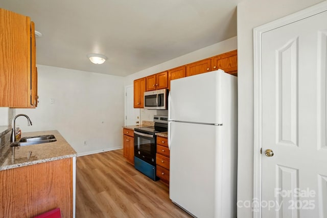 8605 Sawleaf Ct, Charlotte, NC 28215 - kitchen with appliances with stainless steel finishes, a sink, light wood finished floors, brown cabinets, and baseboards