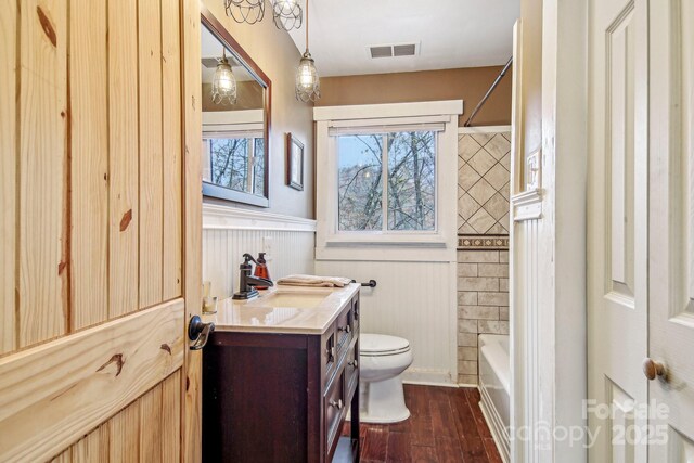 231 Highlands Loop, Maggie Valley, NC 28751 - bathroom featuring vanity, a wainscoted wall, toilet, wood finished floors, and shower / washtub combination