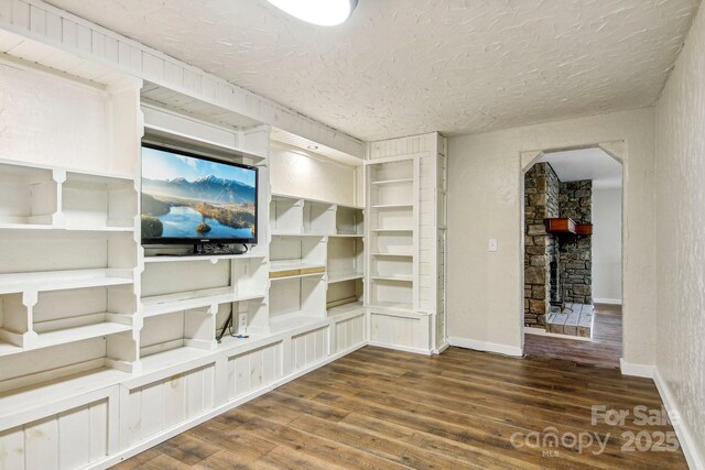 231 Highlands Loop, Maggie Valley, NC 28751 - unfurnished living room featuring wood finished floors, a textured ceiling, baseboards, and arched walkways