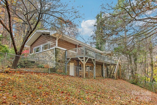 231 Highlands Loop, Maggie Valley, NC 28751 - view of front of property featuring stone siding, stairs, a deck, and a fenced backyard
