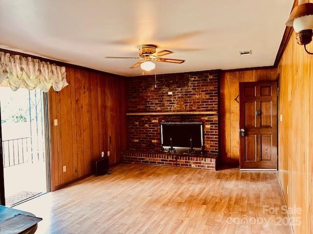 6714 Old Shelby Rd, Vale, NC 28168 - unfurnished living room featuring a fireplace, ceiling fan, wood walls, and wood finished floors