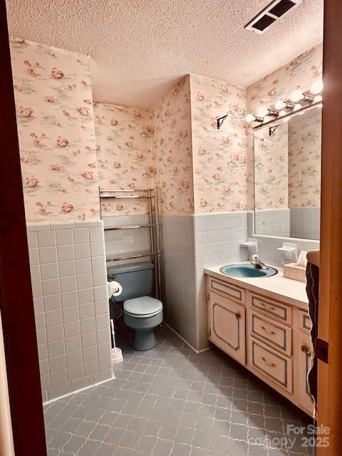 6714 Old Shelby Rd, Vale, NC 28168 - bathroom featuring a wainscoted wall, a textured ceiling, wallpapered walls, toilet, and vanity
