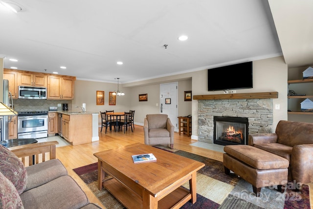 408 Bowling Park Rd, Asheville, NC 28803 - living room featuring light wood finished floors, ornamental molding, a chandelier, a stone fireplace, and recessed lighting
