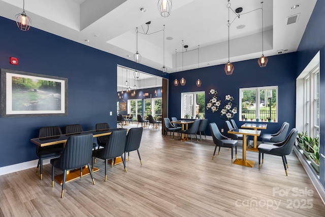 408 Bowling Park Rd, Asheville, NC 28803 - dining space featuring an accent wall, wood finished floors, a tray ceiling, and baseboards