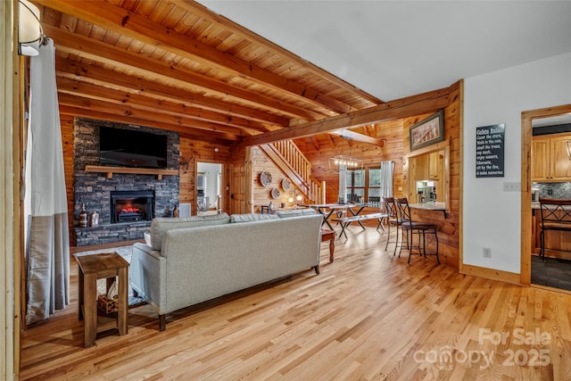 101 Trinity Dr, Clyde, NC 28721 - living room featuring light wood-style floors, wood walls, beam ceiling, a stone fireplace, and baseboards