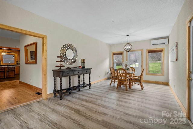 101 Trinity Dr, Clyde, NC 28721 - dining area with a wall unit AC, wood finished floors, a chandelier, and baseboards