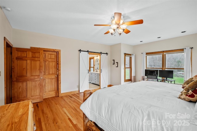 101 Trinity Dr, Clyde, NC 28721 - bedroom featuring a barn door, light wood-type flooring, and baseboards