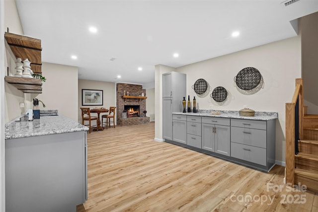 101 Trinity Dr, Clyde, NC 28721 - kitchen featuring gray cabinetry, light wood-style flooring, open shelves, a brick fireplace, and recessed lighting
