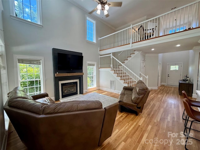 4230 Berry Hill Ct, Concord, NC 28025 - living area with a high ceiling, ceiling fan, stairs, a fireplace with flush hearth, and light wood-type flooring