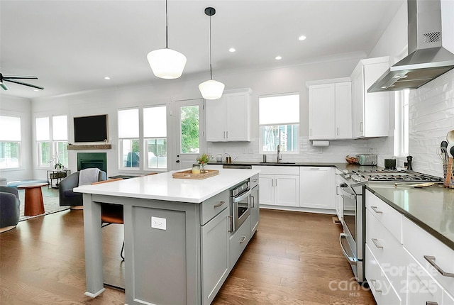 2600 Palm Ave, Charlotte, NC 28205 - kitchen featuring wall chimney exhaust hood, appliances with stainless steel finishes, a sink, open floor plan, and a kitchen island