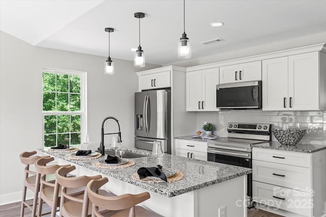 2906 Swicegood Rd, Linwood, NC 27299 - kitchen with stainless steel appliances, a sink, white cabinets, a kitchen island with sink, and a kitchen breakfast bar
