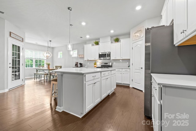 12637 Belmont Mansion Dr, Charlotte, NC 28273 - kitchen with stainless steel appliances, white cabinets, recessed lighting, dark wood finished floors, and tasteful backsplash