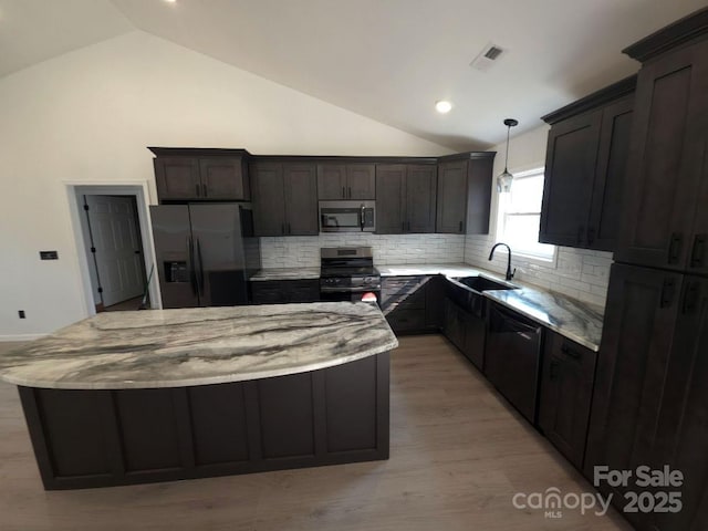 4364 Grover Pl, Granite Falls, NC 28630 - kitchen featuring appliances with stainless steel finishes, vaulted ceiling, a center island, decorative backsplash, and light stone counters