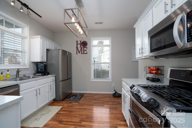 12719 Walking Stick Dr, Charlotte, NC 28278 - kitchen with appliances with stainless steel finishes, a sink, light countertops, white cabinetry, and light wood-style flooring