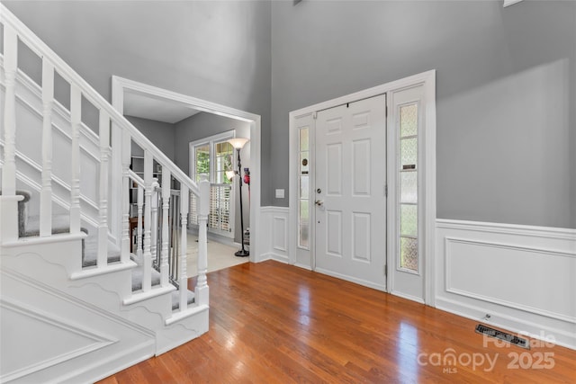 5233 Fairvista Dr, Charlotte, NC 28269 - foyer entrance featuring stairs, wood finished floors, a wainscoted wall, and a decorative wall