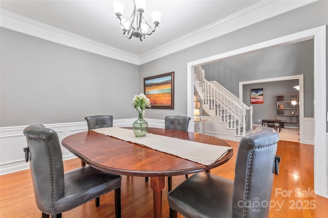 5233 Fairvista Dr, Charlotte, NC 28269 - dining room with a chandelier, stairway, ornamental molding, a wainscoted wall, and light wood-style flooring