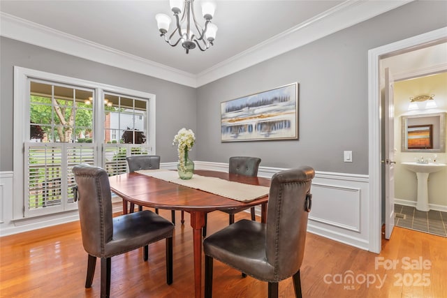 5233 Fairvista Dr, Charlotte, NC 28269 - dining space featuring a chandelier, ornamental molding, a wainscoted wall, and light wood finished floors
