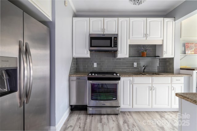 524 Hawthorne Ln, Charlotte, NC 28204 - kitchen featuring stainless steel appliances, a sink, white cabinets, light wood-type flooring, and ornamental molding
