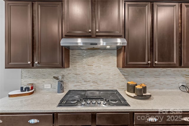 11209 Flenniken Ct, Charlotte, NC 28277 - kitchen with under cabinet range hood, stainless steel gas stovetop, dark brown cabinets, and light countertops