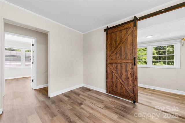 2009 Auten Rd, Gastonia, NC 28054 - unfurnished room featuring light wood-type flooring, baseboards, crown molding, a barn door, and plenty of natural light