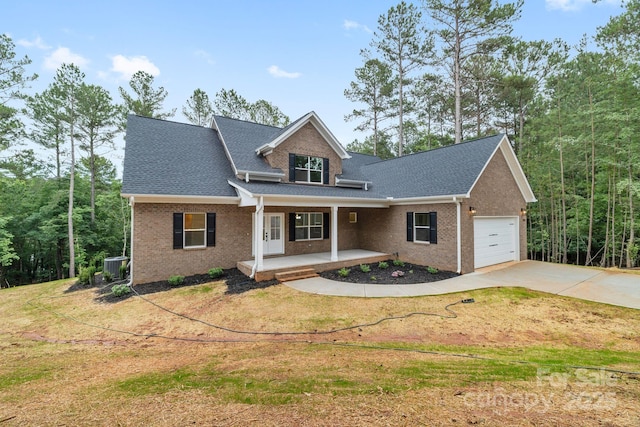 5025 Harbor View Dr E, Granite Falls, NC 28630 - view of front facade featuring covered porch, an attached garage, driveway, brick siding, and central AC unit