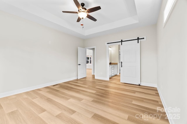 5025 Harbor View Dr E, Granite Falls, NC 28630 - unfurnished bedroom featuring a barn door, a raised ceiling, light wood finished floors, and baseboards