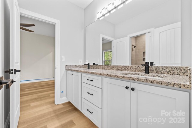 5025 Harbor View Dr E, Granite Falls, NC 28630 - bathroom with double vanity, wood finished floors, baseboards, a tile shower, and a ceiling fan