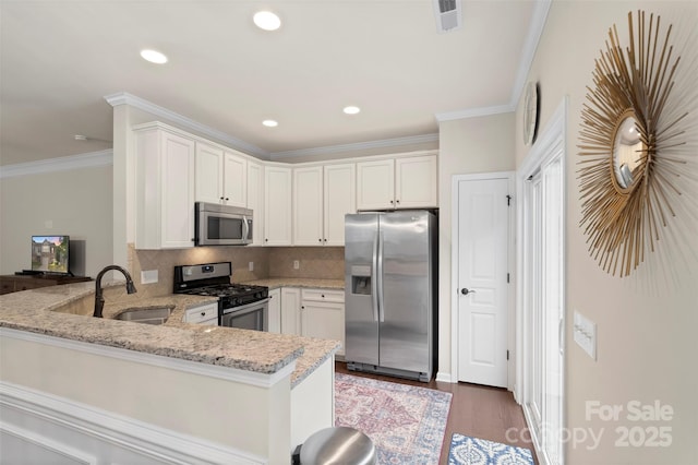 4278 Park S Station Blvd, Charlotte, NC 28210 - kitchen featuring appliances with stainless steel finishes, a peninsula, ornamental molding, light stone countertops, and a sink