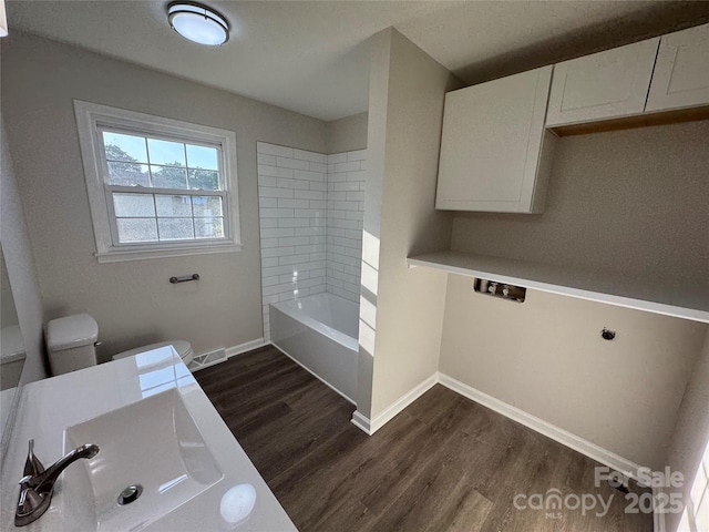 1735 Hollandale Dr, Gastonia, NC 28054 - full bath featuring wood finished floors, toilet, baseboards, and washtub / shower combination
