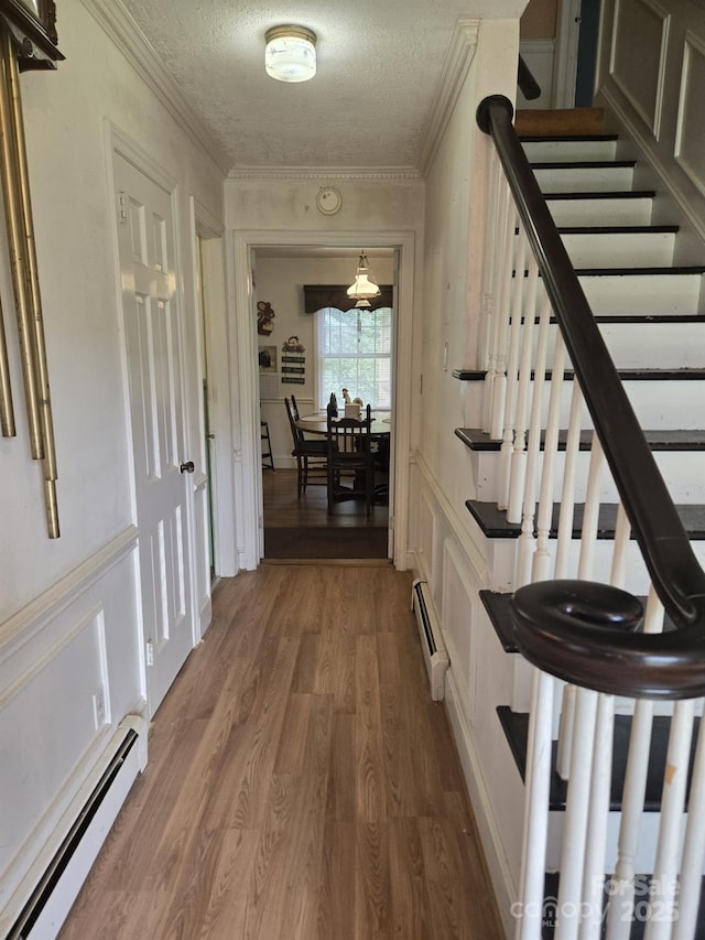 9225 Robinson Church Rd, Charlotte, NC 28215 - hallway with a baseboard heating unit, wood finished floors, crown molding, stairs, and a textured ceiling