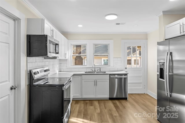 1102 Venus St, Kannapolis, NC 28083 - kitchen featuring stainless steel appliances, a sink, ornamental molding, decorative backsplash, and light wood-style floors