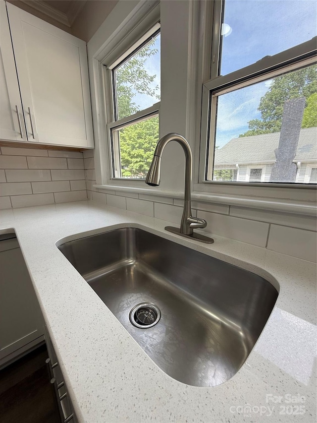 1102 Venus St, Kannapolis, NC 28083 - kitchen view of a sink, backsplash, white cabinetry, and light stone counters