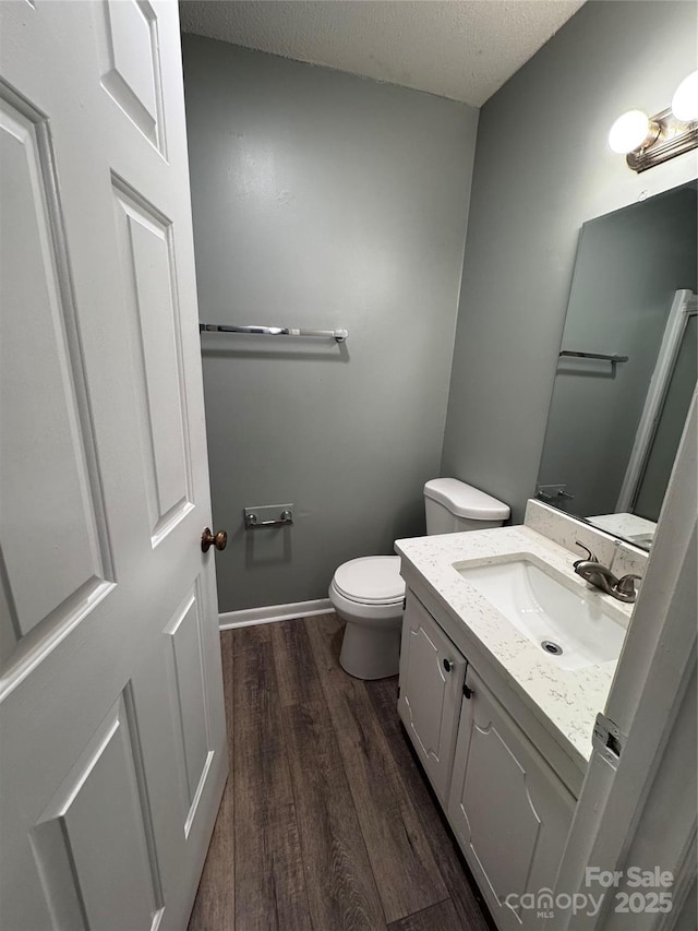 2106 S Main St, Kannapolis, NC 28081 - bathroom featuring wood finished floors, vanity, toilet, a textured ceiling, and baseboards
