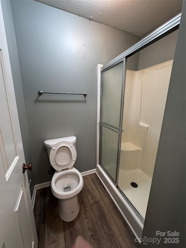 2106 S Main St, Kannapolis, NC 28081 - bathroom featuring wood finished floors, a stall shower, toilet, a textured ceiling, and baseboards