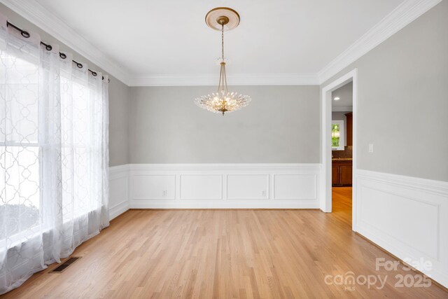 12711 Duncourtney Ln, Charlotte, NC 28277 - spare room featuring a chandelier, light wood finished floors, a wainscoted wall, and crown molding