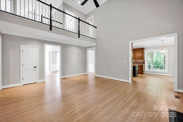 12711 Duncourtney Ln, Charlotte, NC 28277 - unfurnished living room with baseboards, a ceiling fan, light wood-type flooring, a high ceiling, and ornamental molding