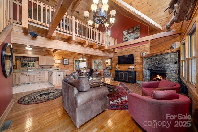 339 Tsalagi Trl, Maggie Valley, NC 28751 - living room with light wood finished floors, wooden walls, a chandelier, a fireplace, and wooden ceiling with exposed beams