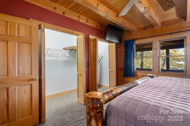 339 Tsalagi Trl, Maggie Valley, NC 28751 - bedroom with carpet, wooden ceiling with exposed beams, baseboards, two closets, and wooden walls
