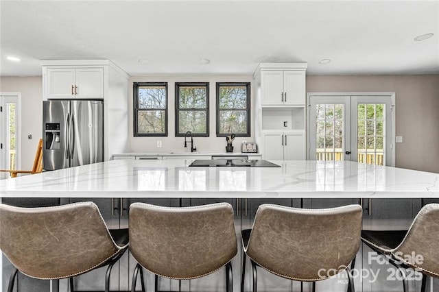 137 Weaver Ct, Lake Lure, NC 28746 - kitchen featuring stainless steel refrigerator with ice dispenser, a sink, black electric stovetop, light stone counters, and white cabinets
