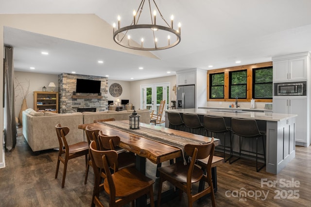 137 Weaver Ct, Lake Lure, NC 28746 - dining room with lofted ceiling, dark wood-type flooring, a chandelier, recessed lighting, and a stone fireplace