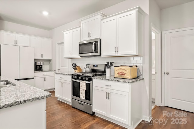 461 Misty Law Ln, Clover, SC 29710 - kitchen with appliances with stainless steel finishes, white cabinetry, wood finished floors, and light stone counters