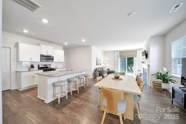461 Misty Law Ln, Clover, SC 29710 - kitchen featuring stainless steel microwave, range with gas stovetop, decorative backsplash, light stone countertops, and open floor plan