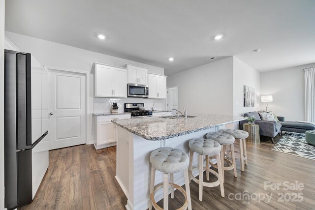 461 Misty Law Ln, Clover, SC 29710 - kitchen with appliances with stainless steel finishes, dark wood-type flooring, a kitchen breakfast bar, open floor plan, and white cabinets