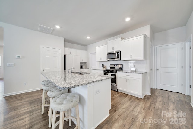 461 Misty Law Ln, Clover, SC 29710 - kitchen with appliances with stainless steel finishes, wood finished floors, a kitchen breakfast bar, an island with sink, and white cabinetry