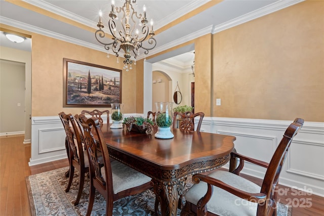 10620 Euclid Ave NW, Concord, NC 28027 - dining room featuring arched walkways, wood-type flooring, a chandelier, wainscoting, and crown molding